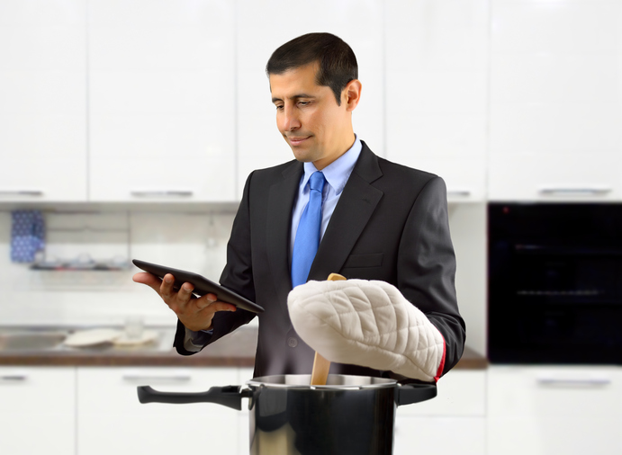 a businessman cooking while following a recipe on a tablet