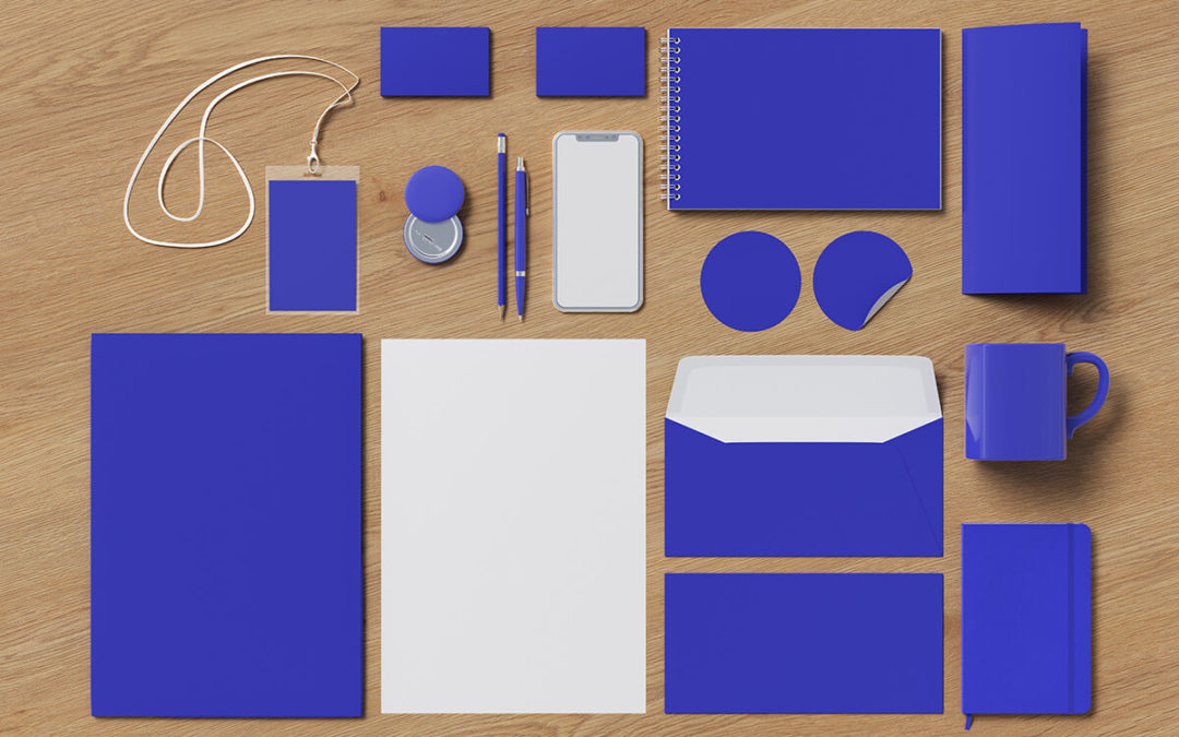 Various blue office supplies, including promotional items like notebooks and pens, all arranged neatly on a wooden surface.
