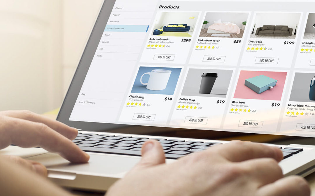 Una persona compra en línea usando una computadora portátil, mostrando una página web con varios productos y precios de franquicias de mercancías personalizadas, mientras sostiene una tarjeta de crédito.